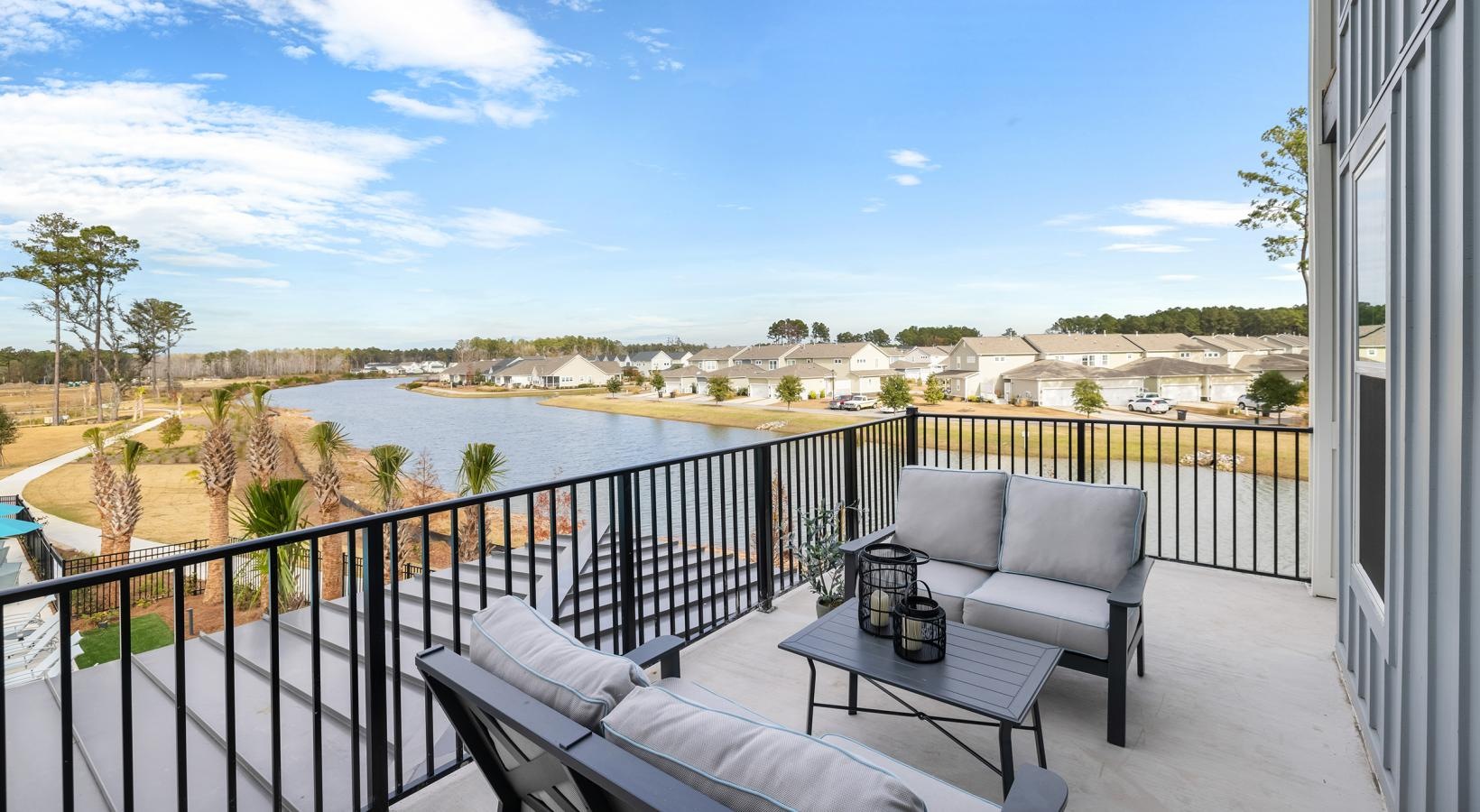 Spacious balconies a deck with chairs and a table with a view of a lake and trees