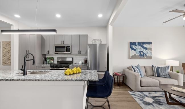 Kitchen and living room at Restore at Carolina Park senior living community in Charleston, SC, featuring wood grain flooring.