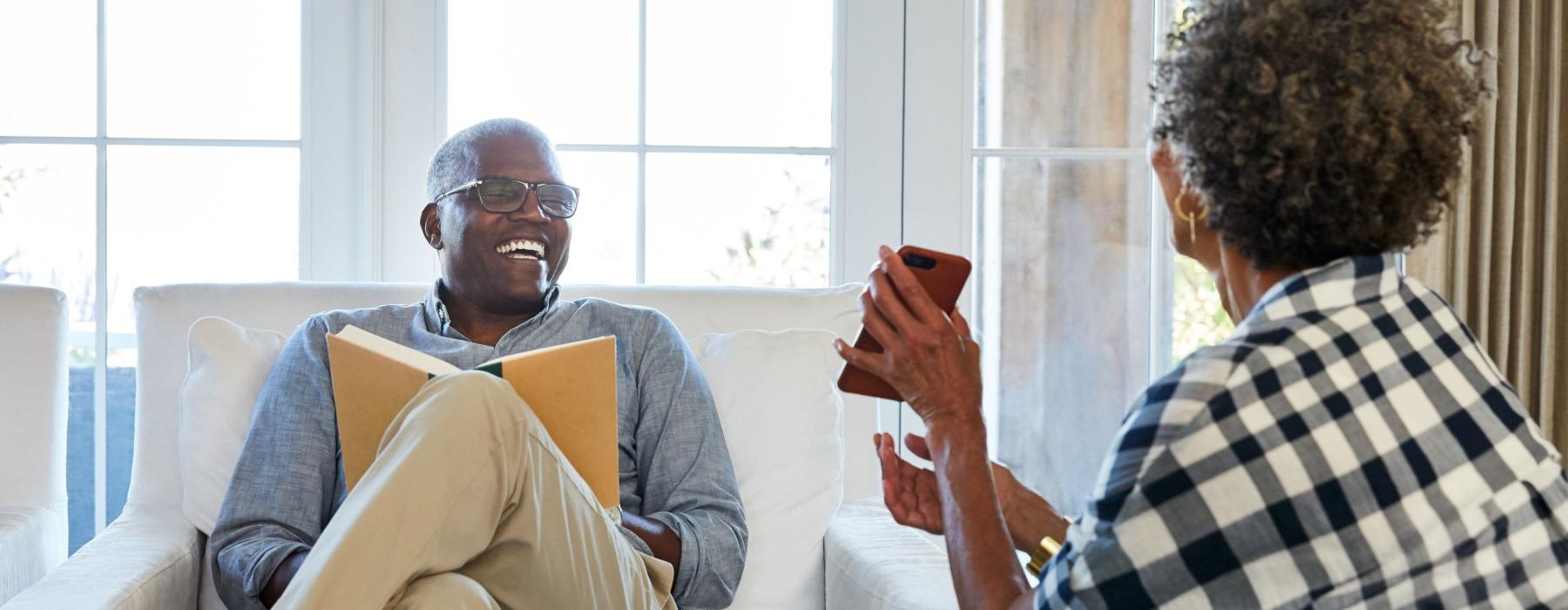 a man and woman sitting on a couch looking at a cell phone