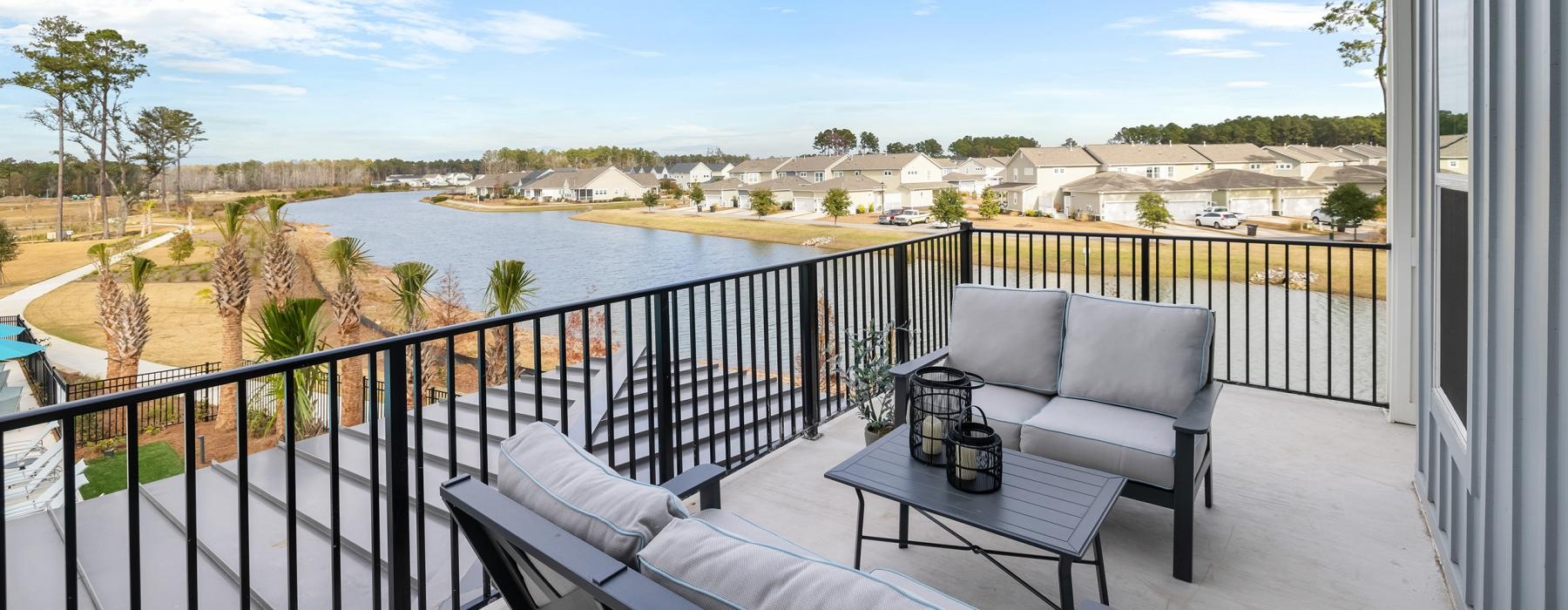 a deck with chairs and a table with a view of a lake and trees