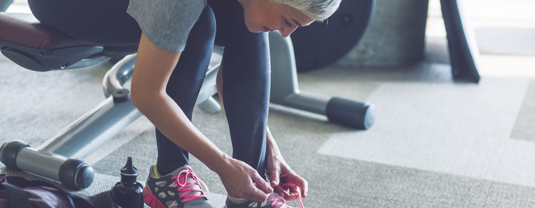 A resident tying her shoes in the fitness center at Restore at Carolina Park senior living community in Charleston, SC.