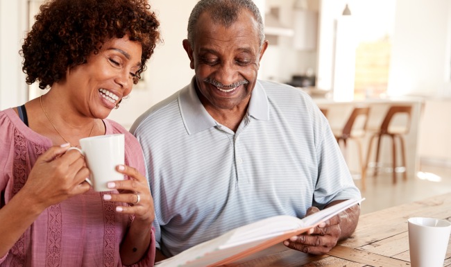 Two residents looking at a book and sipping coffee at Restore at Carolina Park senior living community in Charleston, SC.